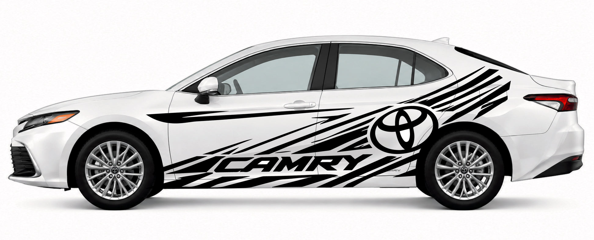 A white Toyota Camry sedan shown in side profile on a light gray studio background, decorated with large black graphic decals including the Toyota emblem and the word CAMRY.