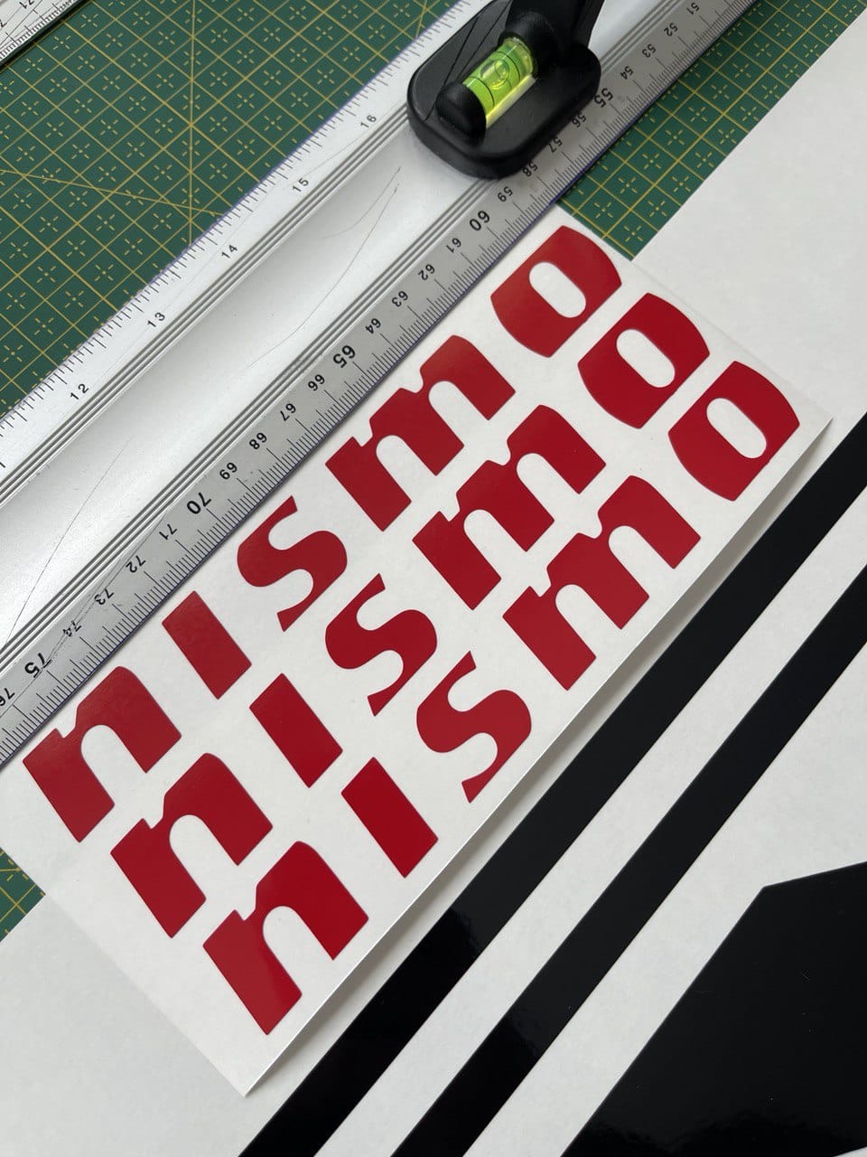 A close-up view of a red and white vinyl sticker with the text 'NISSED' designed for compatibility with Nissan Z cars.
