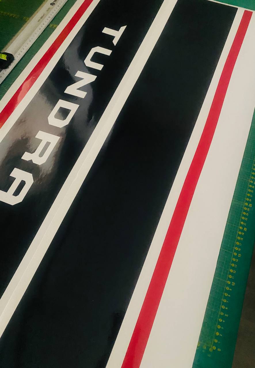 Close-up of a 'Tundra' logo on a black background with red and white stripes.