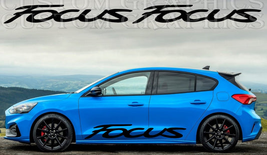 A blue Ford Focus hatchback with a die-cut vinyl graphic decal on the side featuring the word 'FOCUS' in a bold, black font.